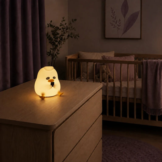 Veilleuse canard assis allumée sur une commode dans une chambre de bébé.