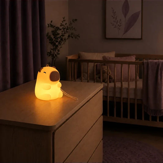 Veilleuse nomade en forme de capybara avec dragonne allumée sur une commode dans une chambre de bébé.