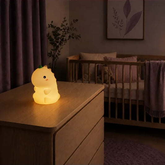 Veilleuse dinosaure T-Rex tactile rechargeable, de couleur orange, allumée sur une commode dans une chambre de bébé.