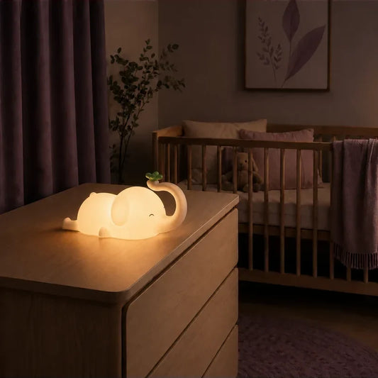 Veilleuse en forme d’éléphant allongé allumée sur une commode dans une chambre de bébé.
