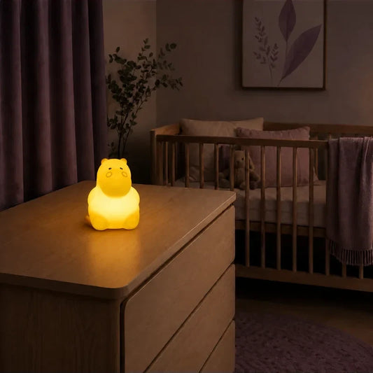 Veilleuse en forme d’hippopotame assis allumée sur une commode dans une chambre de bébé.
