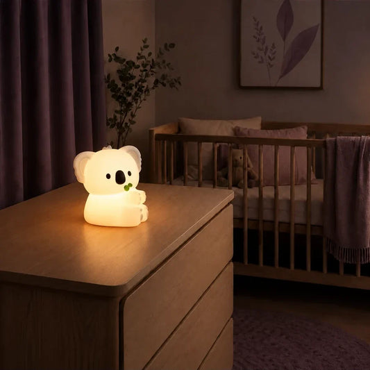 Veilleuse koala avec une feuille d’eucalyptus allumée sur une commode dans une chambre de bébé.
