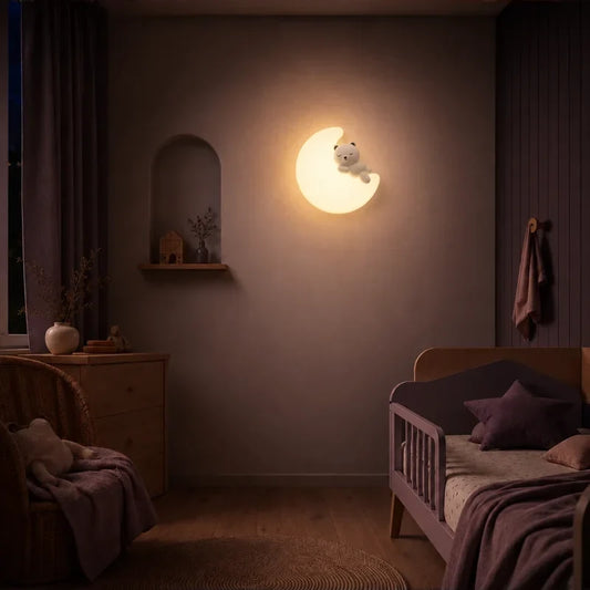 Veilleuse murale lune et ourson allumée dans une chambre de bébé.