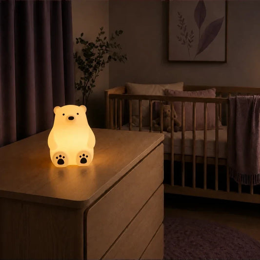 Veilleuse en forme d’ours polaire assis allumée sur une commode dans une chambre de bébé.