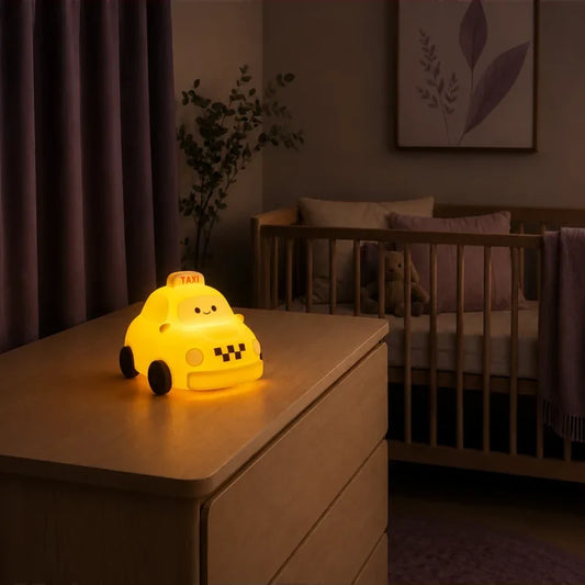 Veilleuse en forme de taxi allumée sur une commode dans une chambre de bébé.