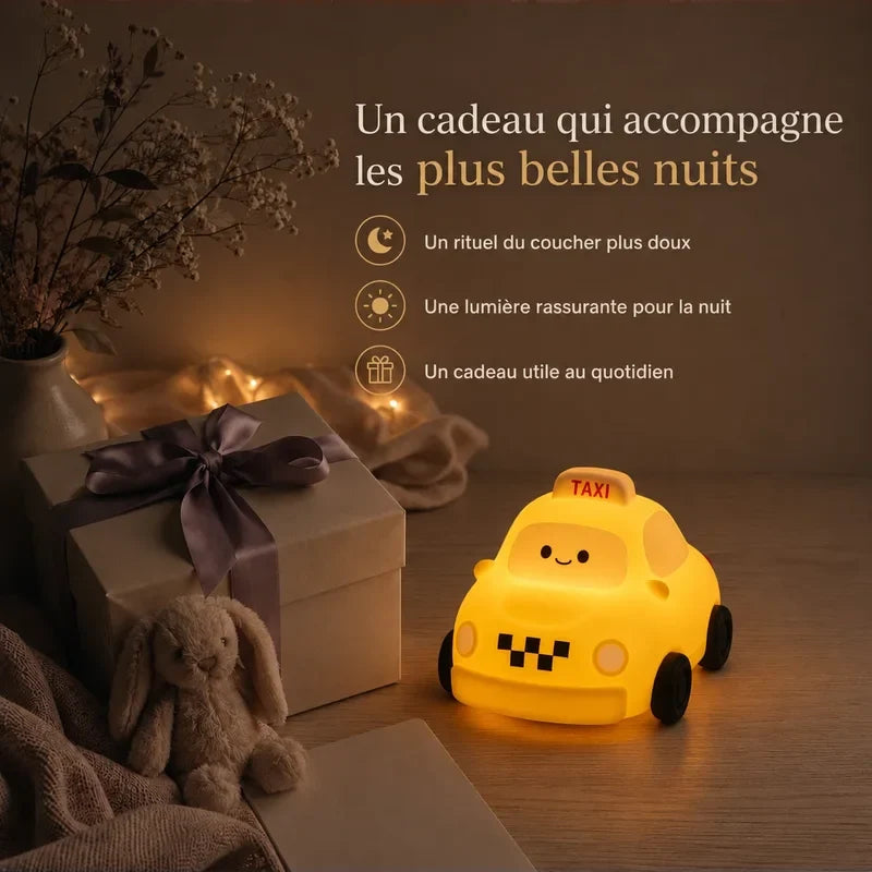 Veilleuse en forme de taxi présentée dans une ambiance cadeau avec une boîte et un ruban.