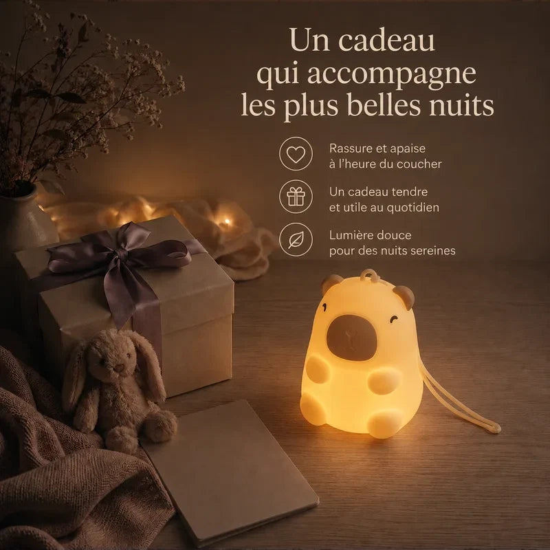 Veilleuse nomade en forme de capybara avec dragonne présentée dans une ambiance cadeau avec une boîte et un ruban.