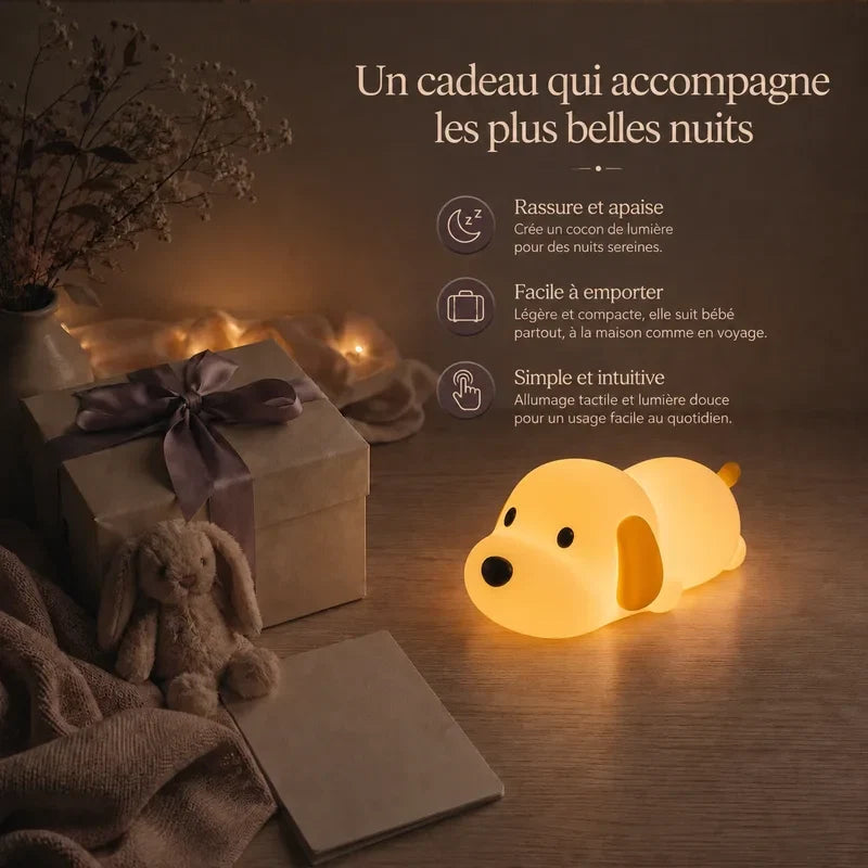 Veilleuse en forme de chien allongé présentée dans une ambiance cadeau avec une boîte et un ruban.