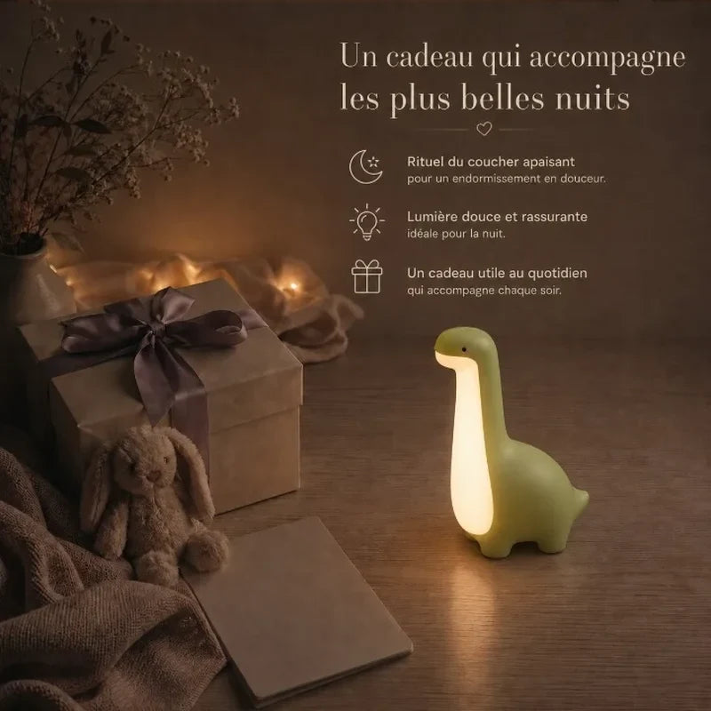 Veilleuse en forme de dinosaure vert à long cou présentée dans une ambiance cadeau avec une boîte et un ruban.
