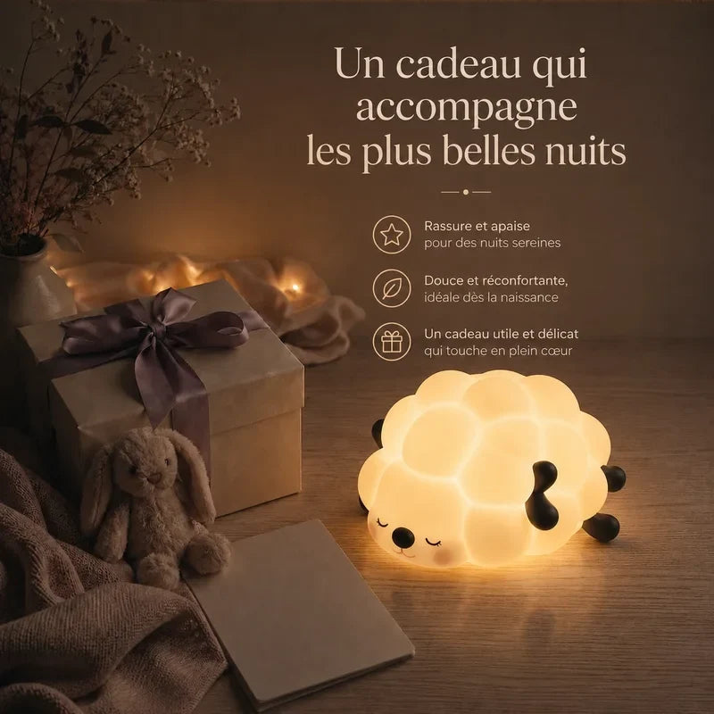 Veilleuse en forme de mouton allongé présentée dans une ambiance cadeau avec une boîte et un ruban.