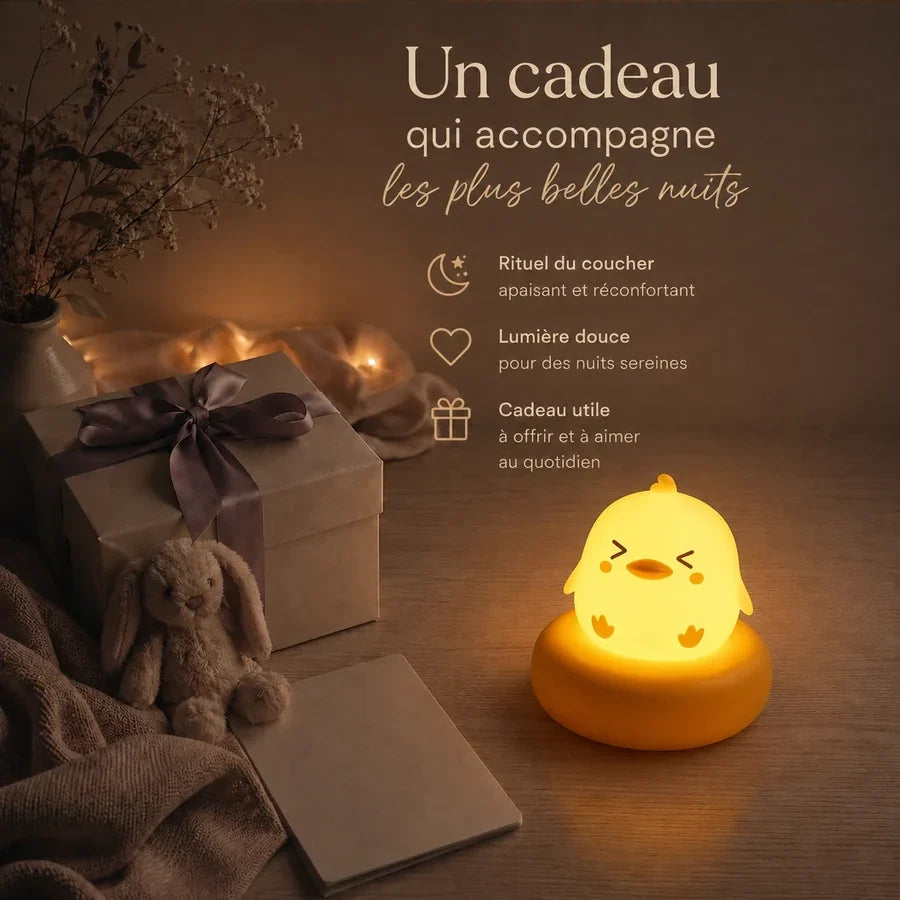 Veilleuse poussin jaune sur socle orange présentée dans une ambiance cadeau avec une boîte et un ruban.