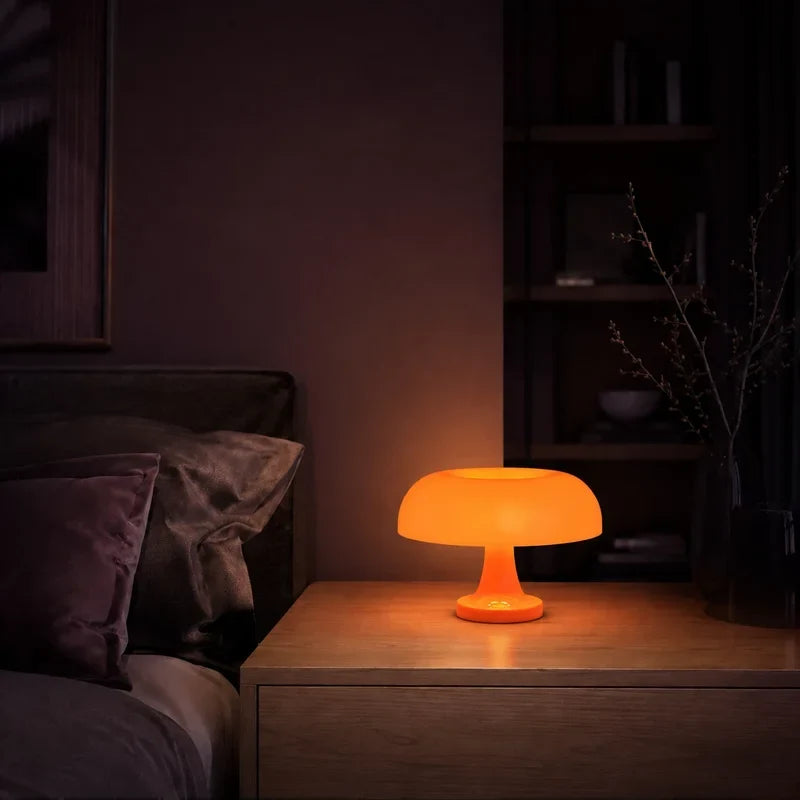 Lampe champignon orange allumée sur une table de chevet dans une ambiance nocturne.