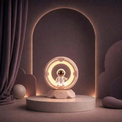 Veilleuse en forme d’astronaute dans un anneau lumineux allumée sur un podium mauve.