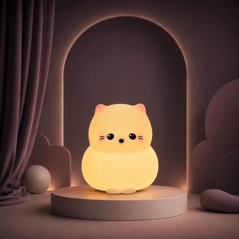 Veilleuse en forme de chat rond allumée sur un podium mauve.