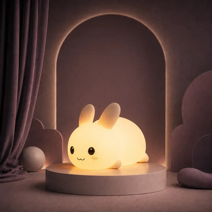 Veilleuse en forme de lapin rond allumée sur un podium mauve.