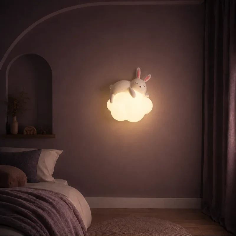 Veilleuse murale nuage et lapin allumée sur un mur dans une chambre d’enfant.