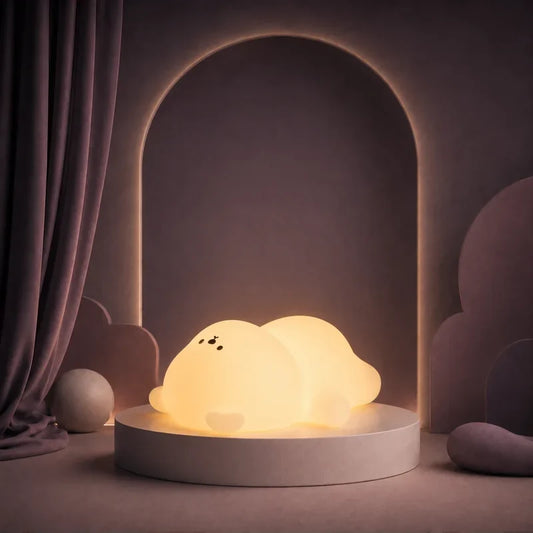 Veilleuse en forme d’ours endormi allongé allumée sur un podium mauve.