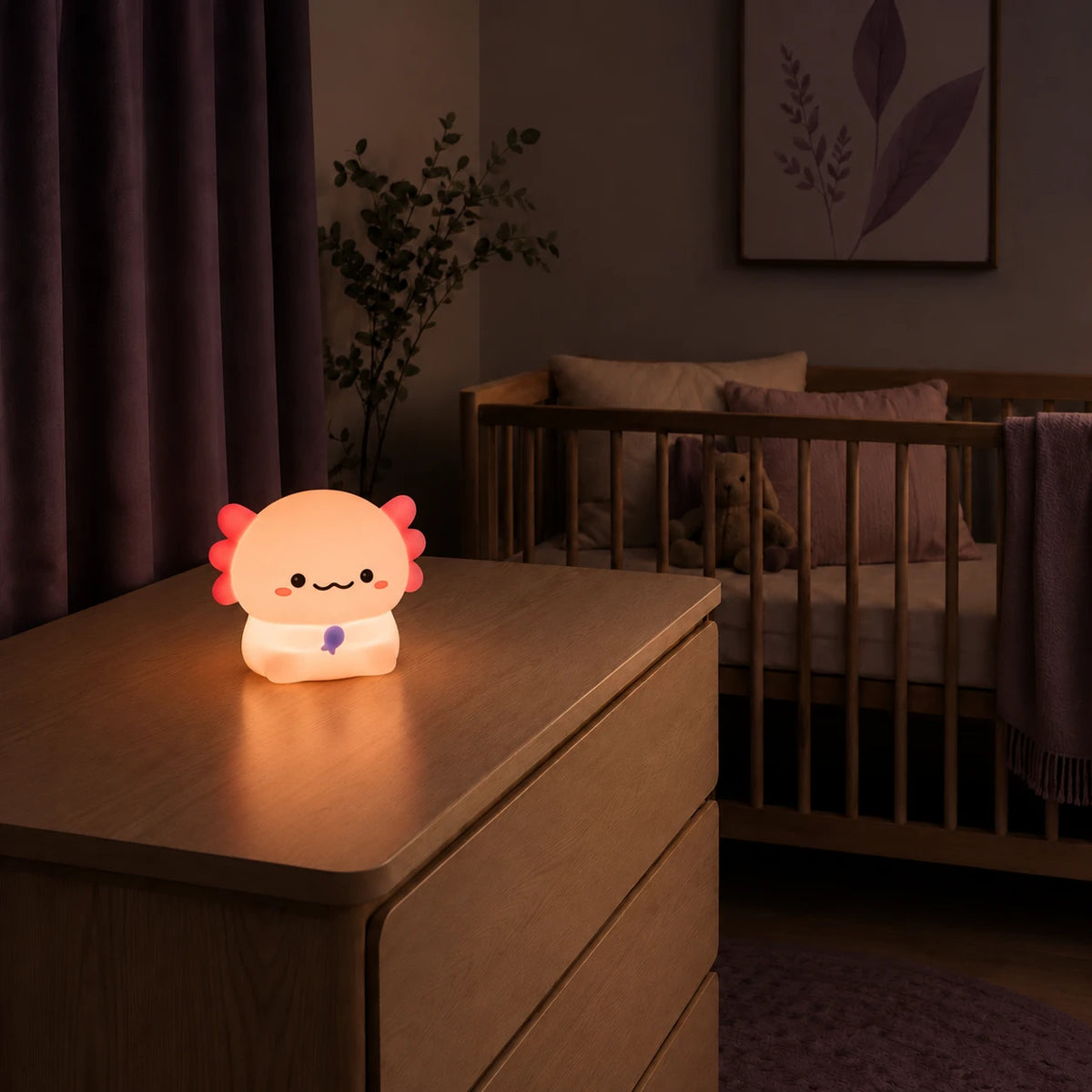 Veilleuse en forme d’axolotl debout allumée sur une commode dans une chambre de bébé.