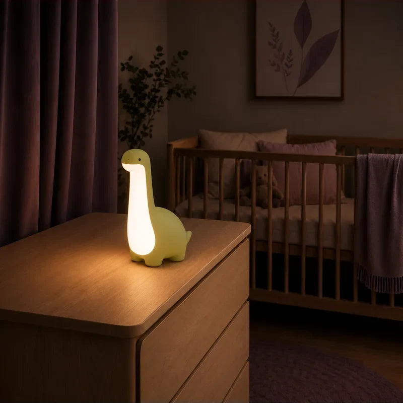 Veilleuse en forme de dinosaure vert à long cou allumée sur une commode dans une chambre de bébé.