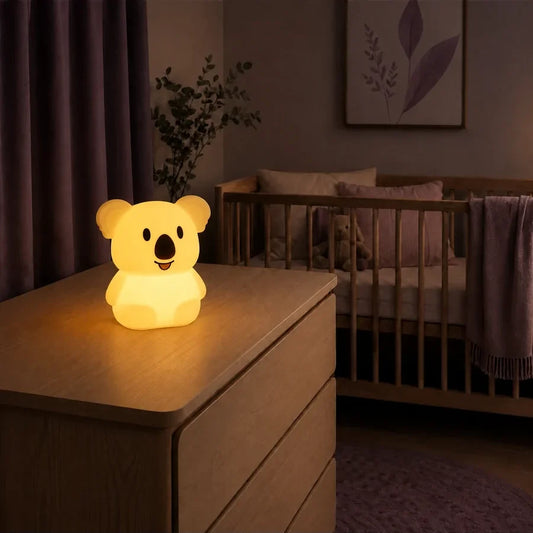 Veilleuse en forme de koala debout allumée sur une commode dans une chambre de bébé.