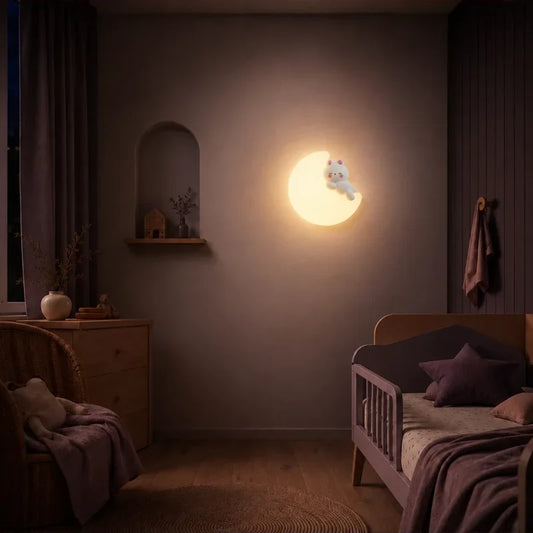 Veilleuse murale lune et chat allumée dans une chambre de bébé.