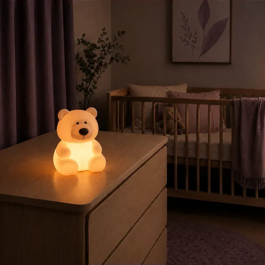 Veilleuse en forme d’ours assis allumée sur une commode dans une chambre de bébé.