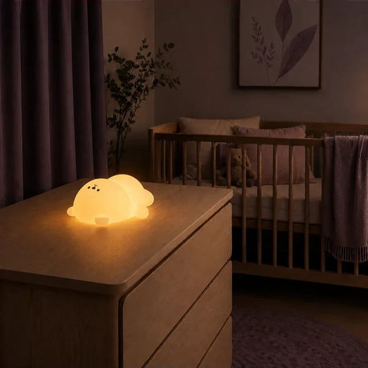 Veilleuse en forme d’ours endormi allongé allumée sur une commode dans une chambre de bébé.