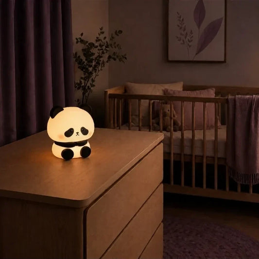 Veilleuse en forme de panda debout allumée sur une commode dans une chambre de bébé.
