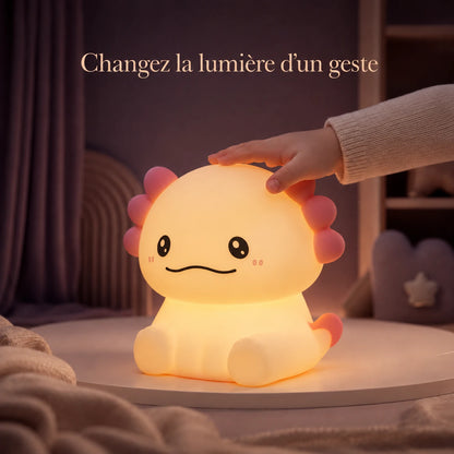 Main d’enfant touchant la veilleuse en forme d’axolotl assis pour changer la lumière.