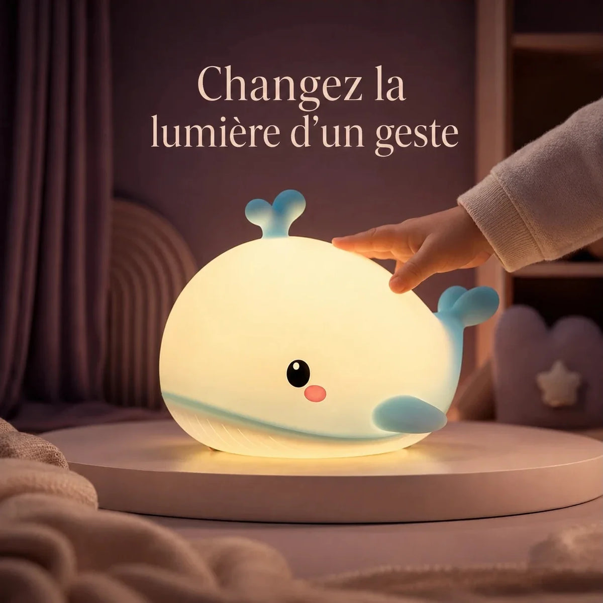 Main d’enfant touchant la veilleuse en forme de baleine bleue pour changer la lumière.