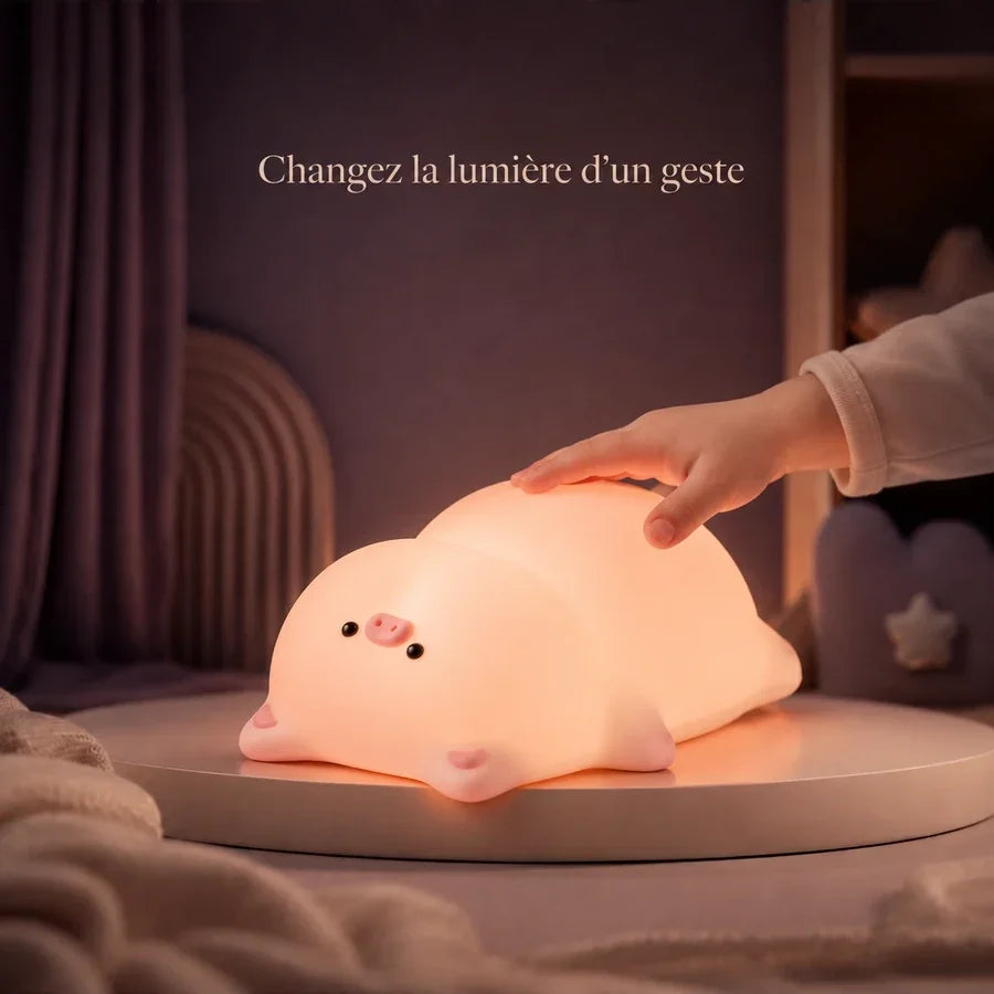 Main d’enfant touchant la veilleuse en forme de cochon allongé pour changer la lumière.