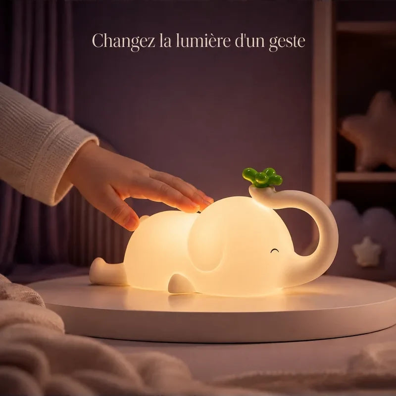 Main touchant la veilleuse en forme d’éléphant allongé pour changer la lumière.