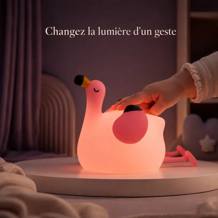 Main d’enfant touchant la veilleuse en forme de flamant rose pour changer la lumière.