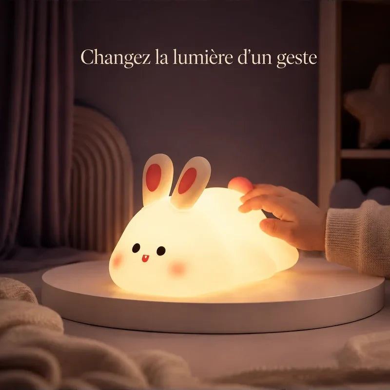 Main touchant la veilleuse en forme de lapin allongé pour changer la lumière.