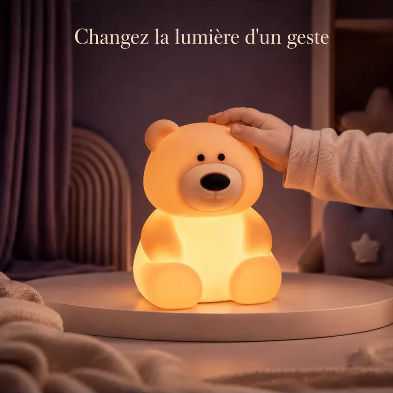 Main touchant la veilleuse en forme d’ours assis pour changer la lumière.