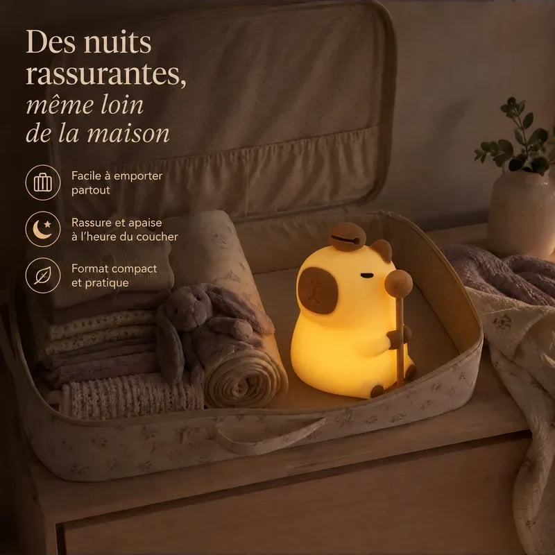 Veilleuse en forme de capybara debout rangée dans une valise pour accompagner un enfant en voyage.