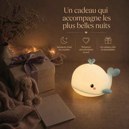 Veilleuse en forme de baleine bleue présentée dans une ambiance cadeau avec une boîte et un ruban.