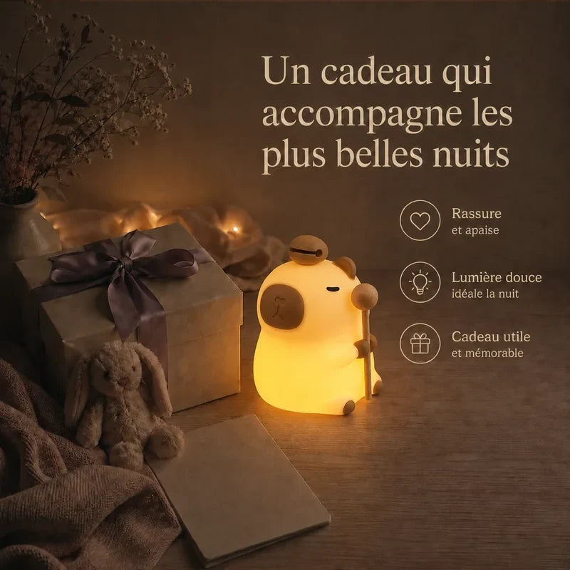 Veilleuse en forme de capybara debout présentée dans une ambiance cadeau avec une boîte et un ruban.