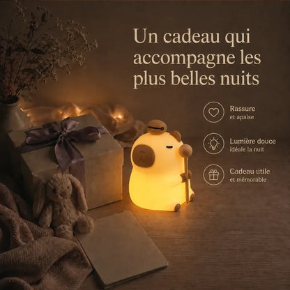 Veilleuse en forme de capybara debout présentée dans une ambiance cadeau avec une boîte et un ruban.