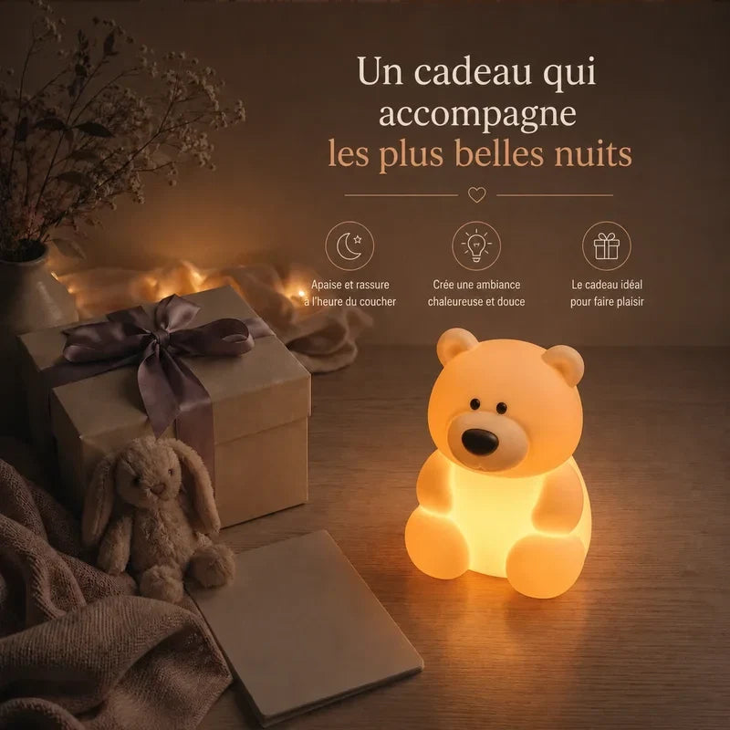 Veilleuse en forme d’ours assis présentée dans une ambiance cadeau avec une boîte et un ruban.