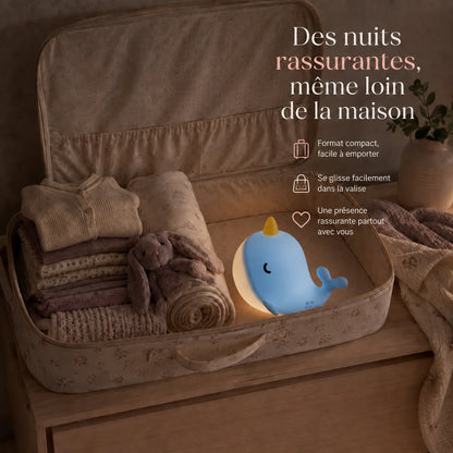 Veilleuse en forme de baleine narval bleue rangée dans une valise pour accompagner un enfant en voyage.