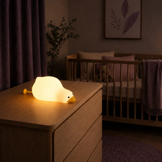 Veilleuse en forme de canard allongé allumée sur une commode dans une chambre de bébé.