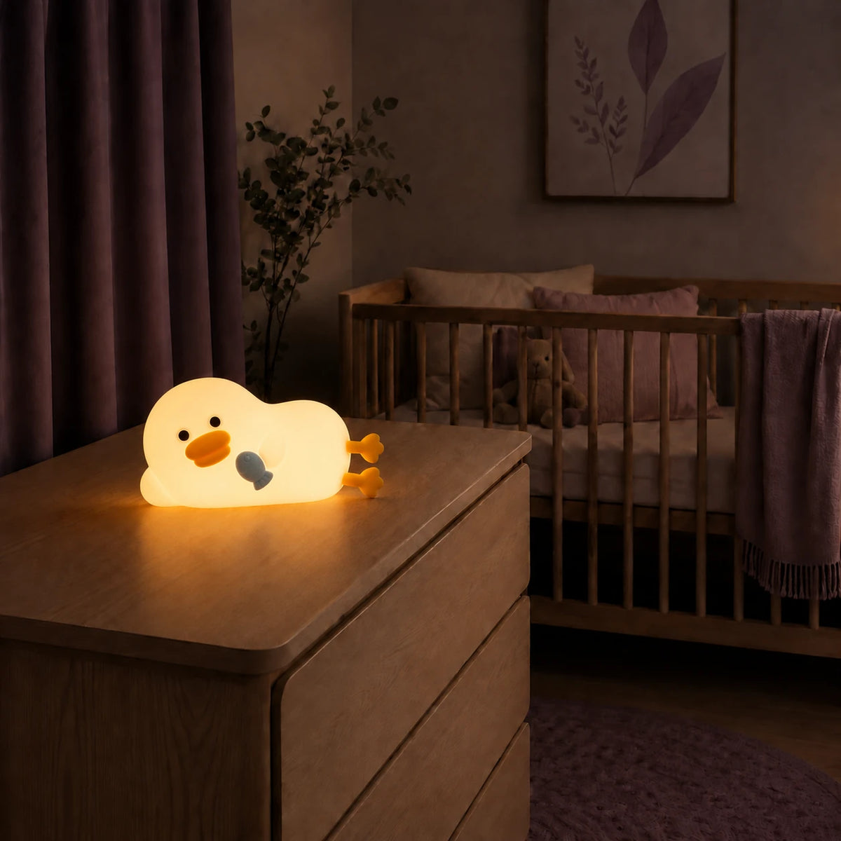 Veilleuse en forme de canard allongé avec un petit poisson bleu allumée sur une commode dans une chambre de bébé.